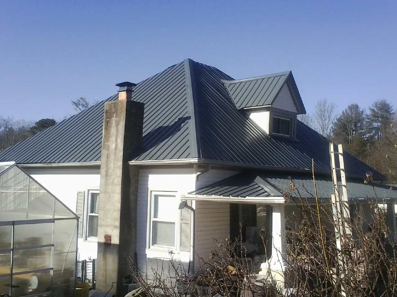 Dark blue standing seam metal roof on a white farmhouse with dormer — Slate & Tile Roof Repair by Roofing Brothers in Jbsa Randolph