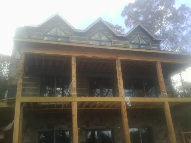 Dormers and porch framing on a large log home under construction — Roof Coating work by our crew in Jbsa Randolph