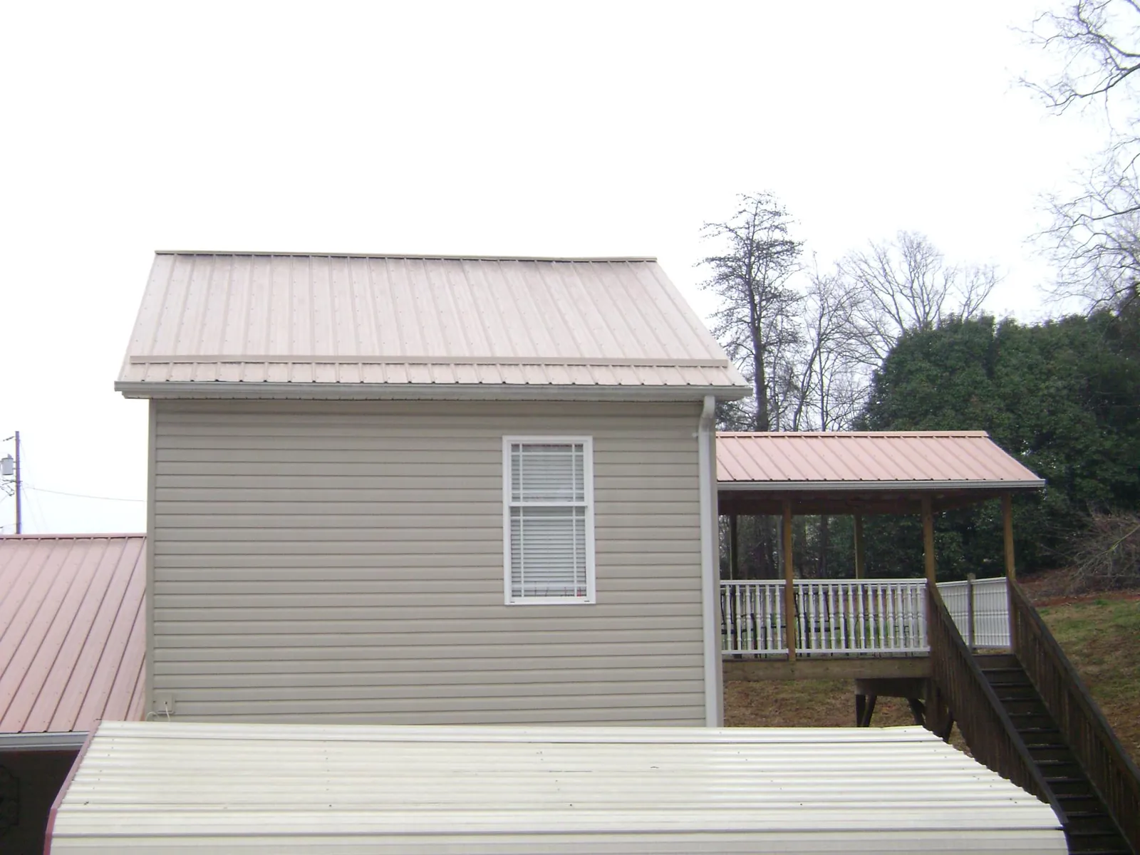 Tan metal roofs on a two story addition and attached porch, from a Roof Replacement job in Jbsa Randolph