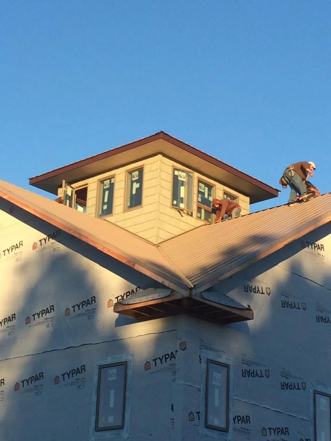 Roofers working around a rooftop cupola on a new metal roof at sunset — Roof Waterproofing in Jbsa Randolph by Roofing Brothers